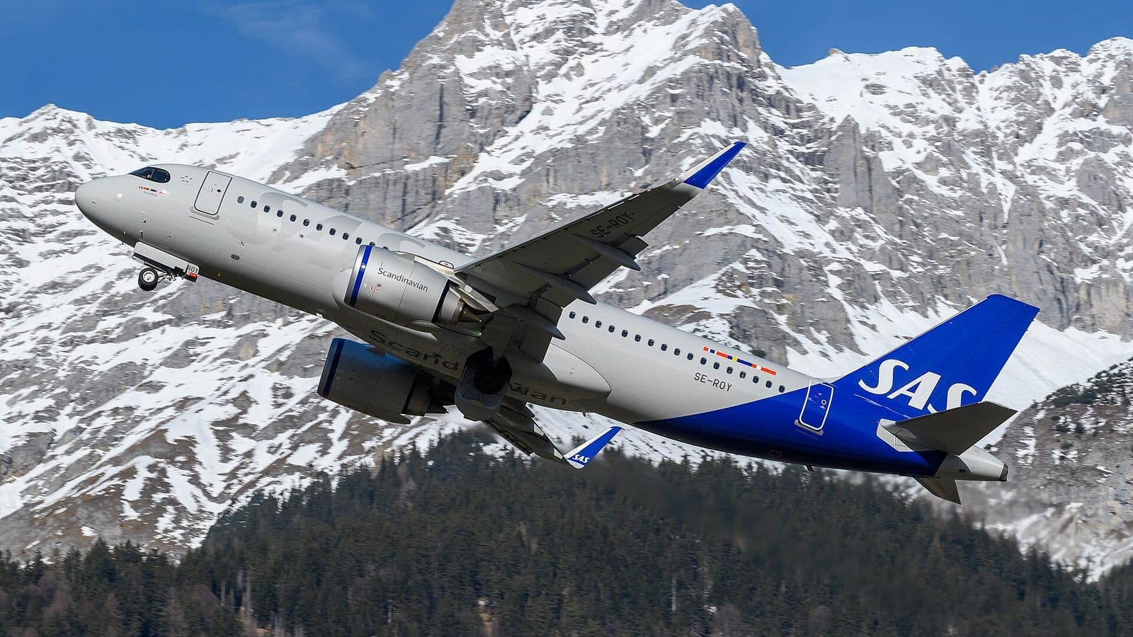 Airbus A320neo de SAS en montée devant des montagnes enneigées